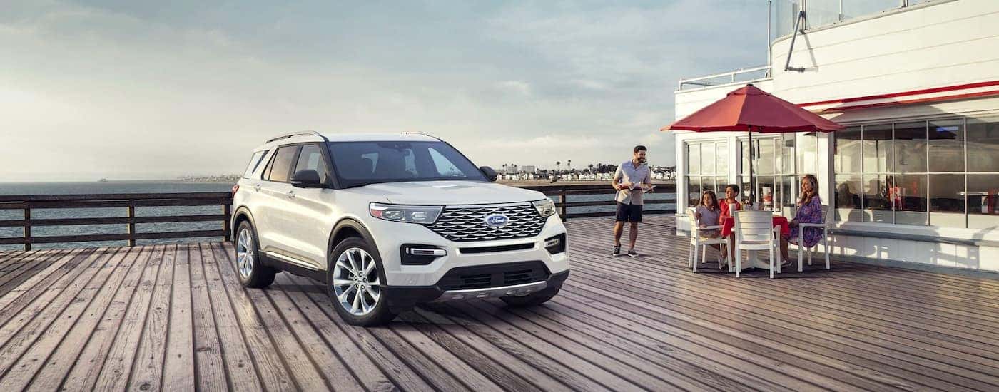 A white 2021 Ford Explorer Hybrid is shown parked next to a family eating on the pier.