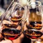 A close up is shown of people toasting wine glasses.