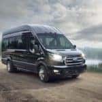 A black 2020 Ford Transit is driving down a dirt road after leaving a Ford commercial vehicle dealer.