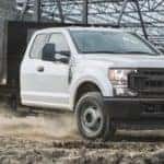 A white 2021 Ford F-350 Chassis cab is parked on dirt at a job site.