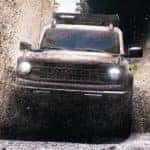 A white 2021 Ford Bronco from a Cincinnati Ford Bronco Dealer is spraying mud while off-roading.