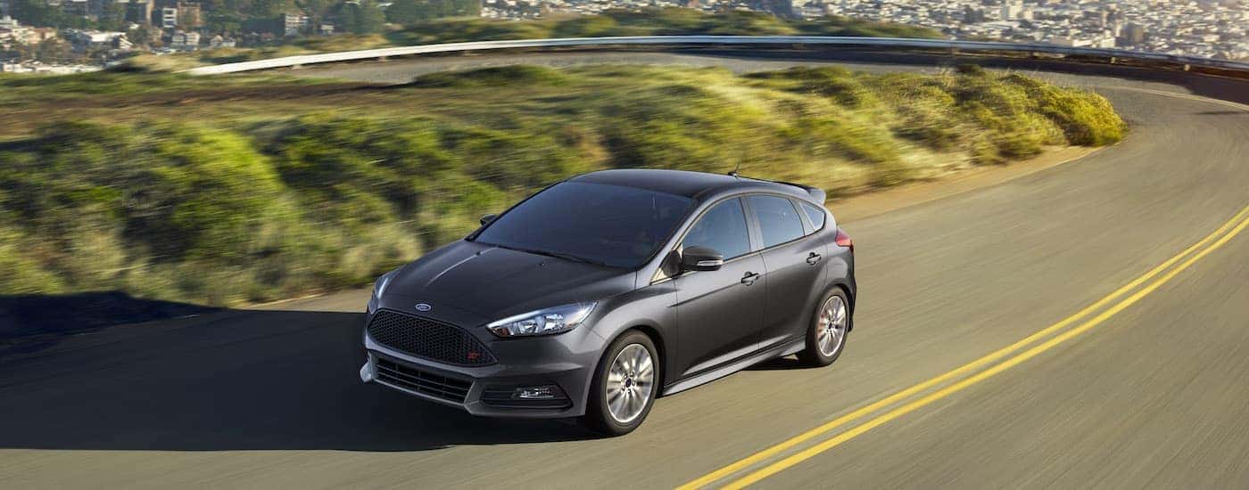 A dark grey 2016 Ford Focus ST driving on a winding road.