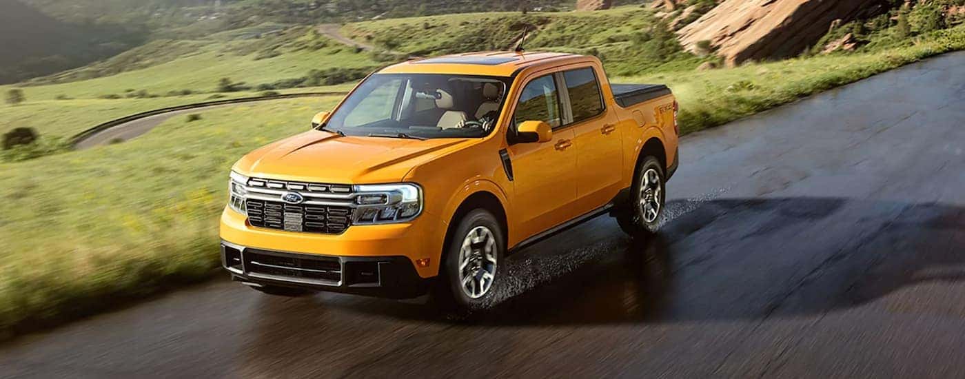 A yellow 2022 Ford Maverick driving past a field.