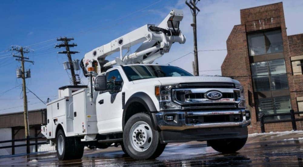 A white 2019 Ford F-600 with a utility upfit is parked on a downtown street.