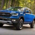 A popular Cincinnati used car, a blue 2019 Ford Ranger, is driving on a tree-lined road.