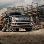 A popular used Ford commercial vehicle, a black 2019 Ford F-350, is being loaded with equipment at a job site.