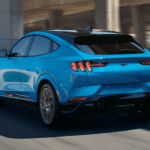 A light blue 2021 Ford Mustang Mach-E is driving on an overpass after leaving the Ford SUV dealer in Cincinnati.