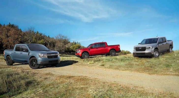 A blue, a red, and a silver 2022 Ford Maverick are shown near a dirt path and trees.