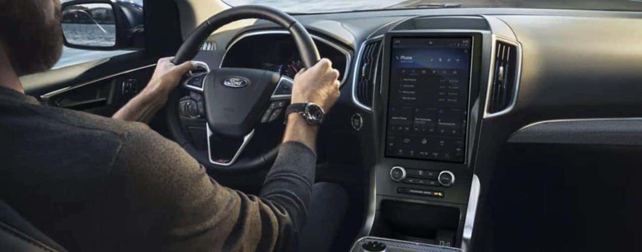 The black interior of a 2022 Ford Edge shows the steering wheel and infotainment screen.