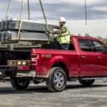 Construction workers are shown loading supplies into the bed of red 2020 Ford F-150.