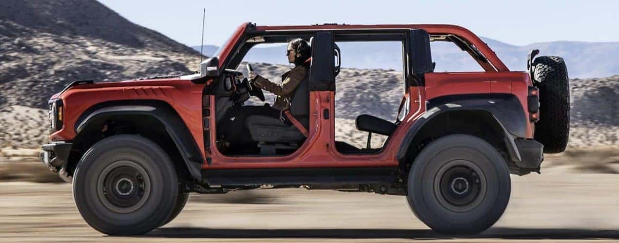 An orange 2022 Ford Bronco is shown from the side off-roading in a desert.