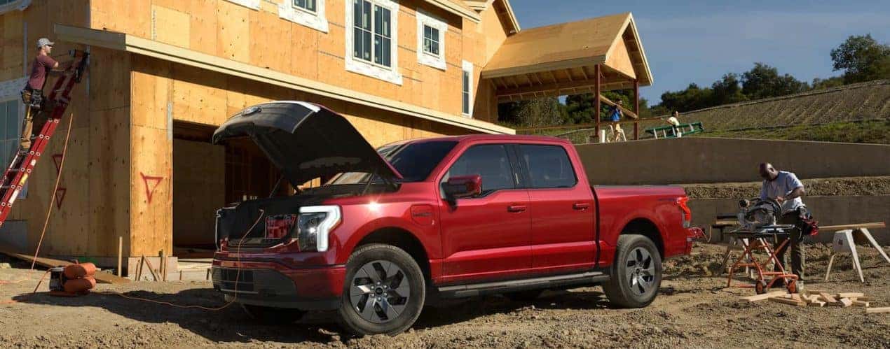 A red 2022 Ford F-150 Lightning is shown parked at a construction site.