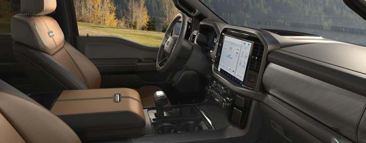 The black and brown interior of a 2022 Ford F-150 Platinum shows the steering wheel and infotainment screen.