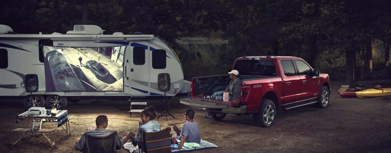A red 2022 Ford F-150 is shown parked at a campsite at night.