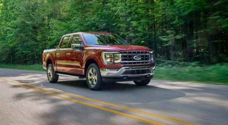 A maroon 2020 Ford F-150 Lariat is shown driving on a tree-lined road after visiting a Mason Ford dealer.