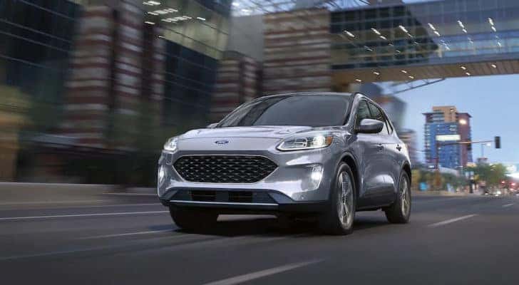 A silver 2021 Ford Escape Titanium is shown driving on a city street.