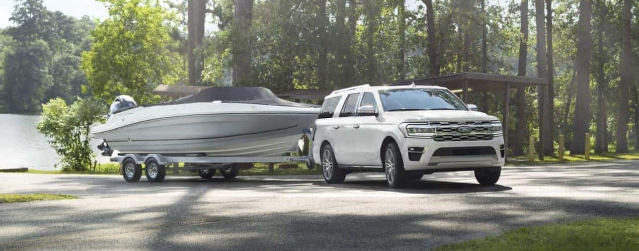 A white 2023 Ford Expedition is shown towing a boat.