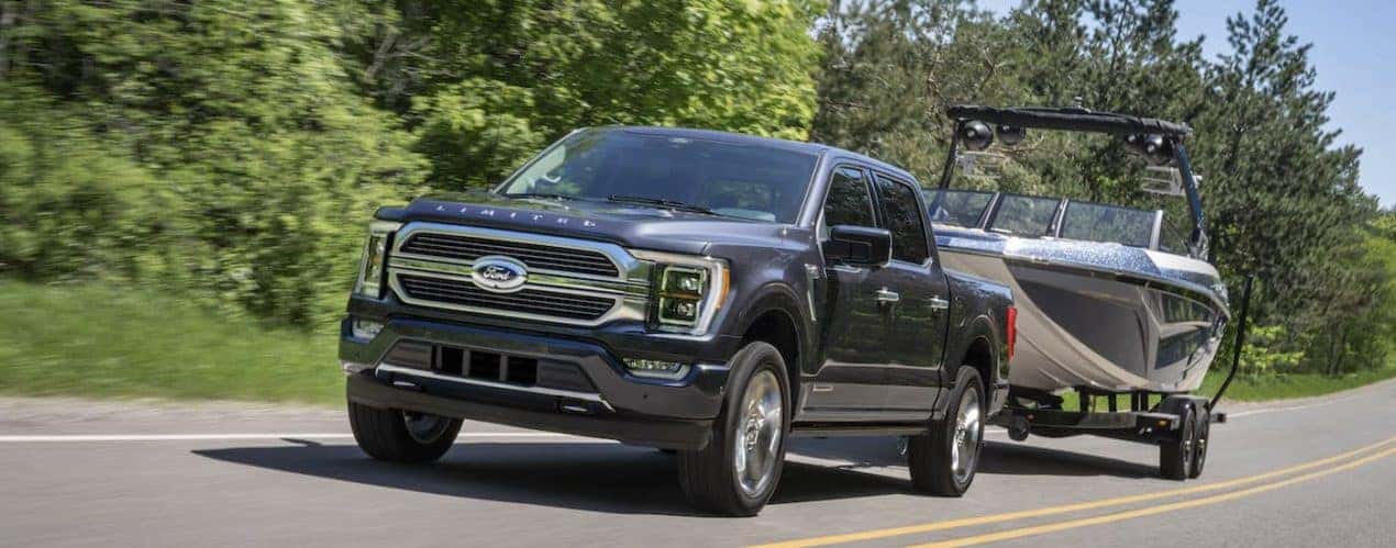 A grey 2023 Ford F-150 Platinum is shown from the front at an angle while towing a boat.