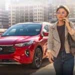 A woman on her cell phone walking away from a red 2023 Ford Escape in a parking lot overlooking the city