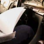 A driver looking at paperwork inside a vehicle.