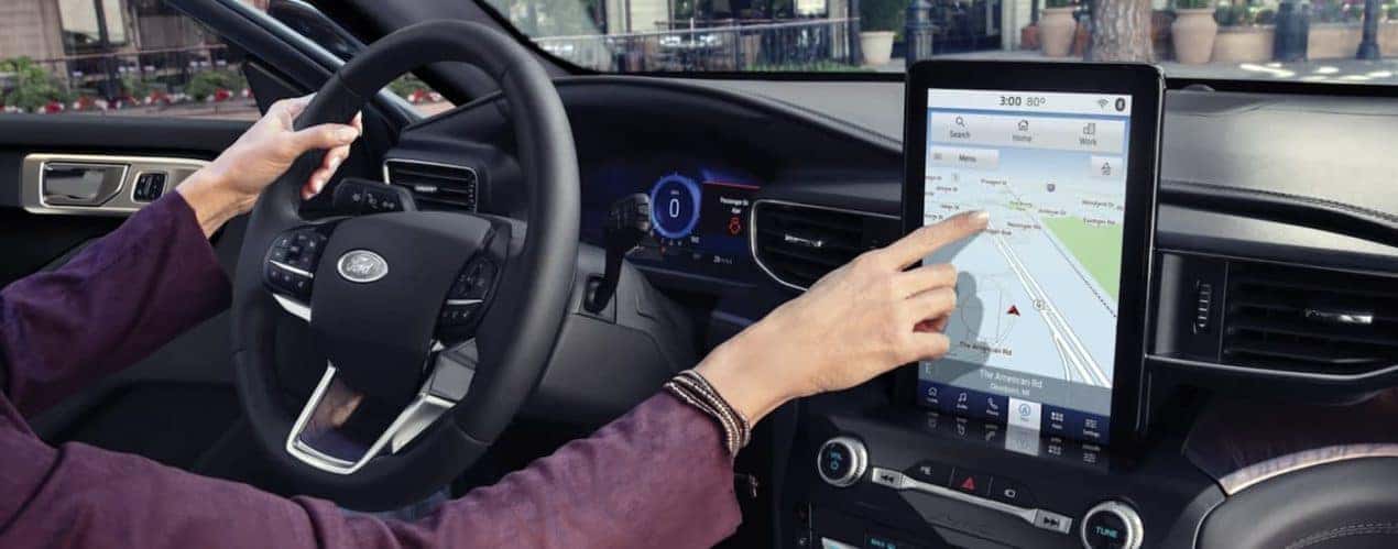 The black interior of a 2023 Ford Explorer shows the steering wheel and infotainment screen.