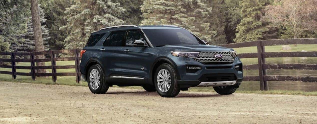 A turquoise 2023 Ford Explorer is shown from the side parked next to a fence.
