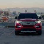 A red 2023 Ford Explorer Limited Hybrid parked in a lot overlooking a city.