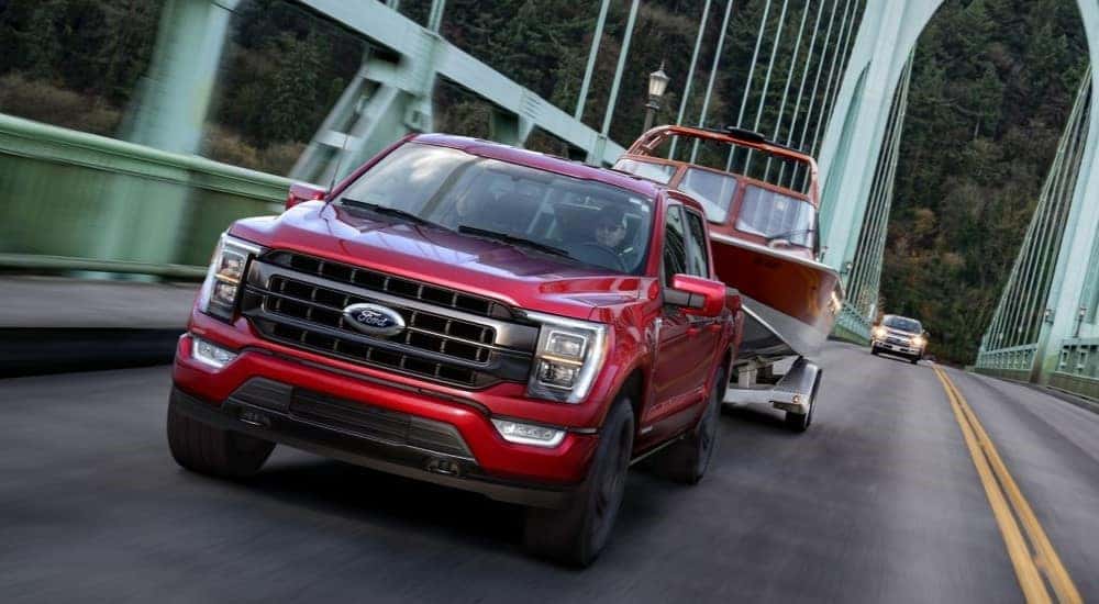 A red 2021 Ford F-150 towing a boat over a bridge.