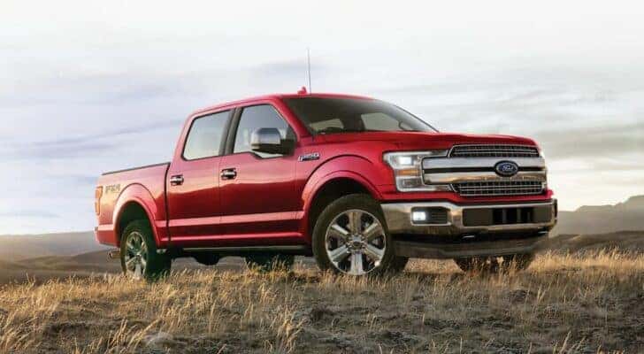 A red 2020 Ford F-150 is shown parked in a dry grassy field after viewing used trucks for sale in Cincinnati.