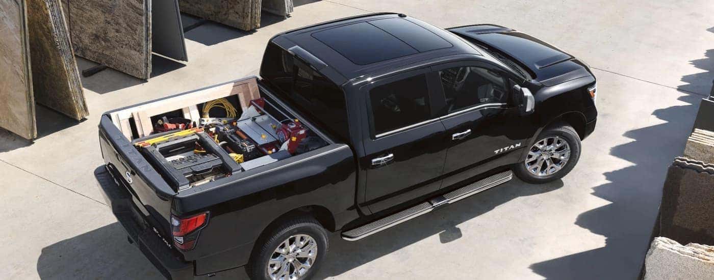 A black 2021 Nissan Titan is shown from above with a bed full of construction equipment.