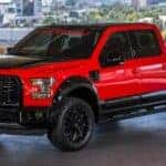 A red and black 2015 Ford F-150 in a parking garage overlooking the city
