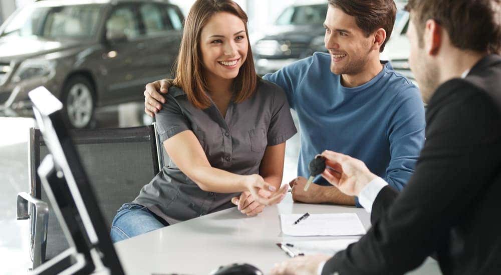 A couple is shown speaking to a salesman about their vehicle's trade-in value.