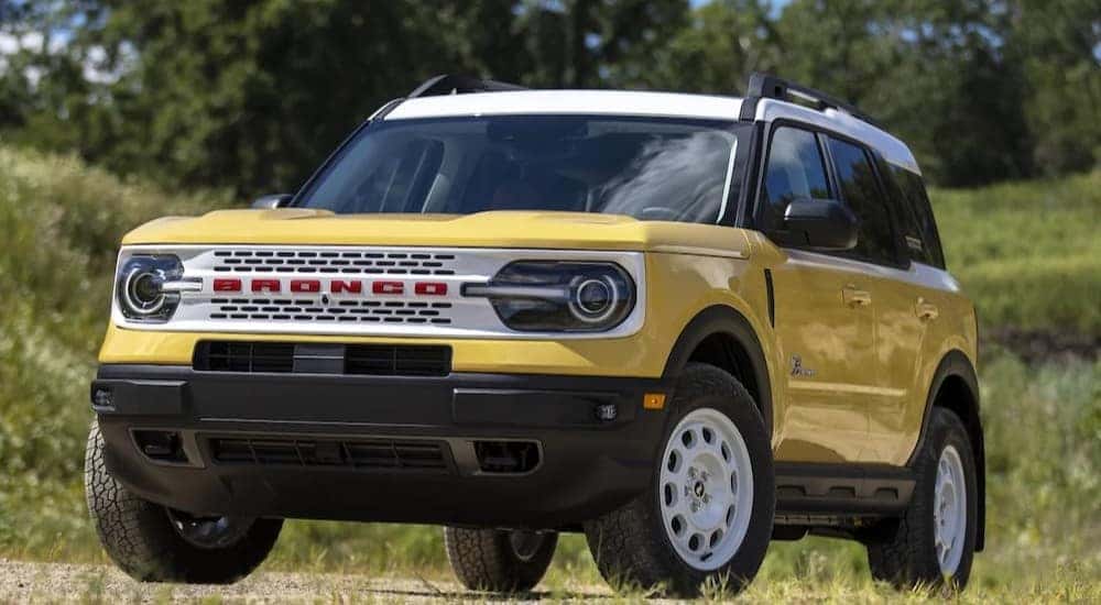 A yellow 2023 Ford Bronco Sport Heritage Limited Edition is shown parked near trees.