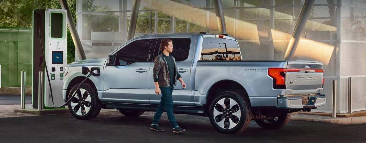 A light blue 2023 Ford F-150 Lightning for sale is shown on a charging station.