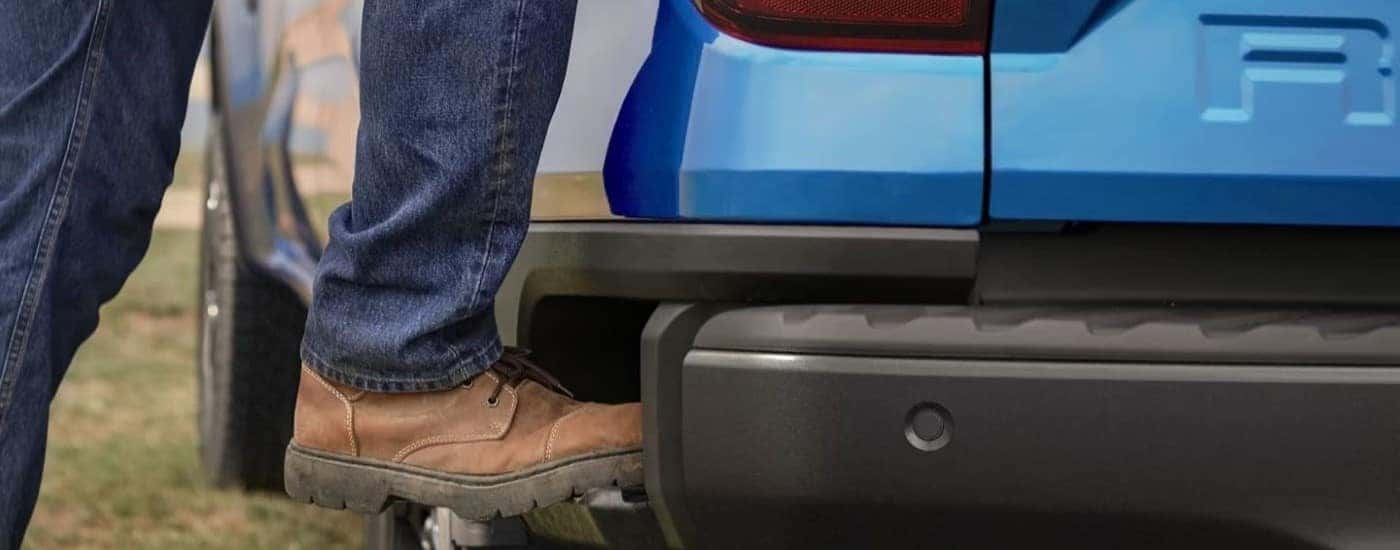 A person is shown using the step on a blue 2024 Ford Ranger for sale.
