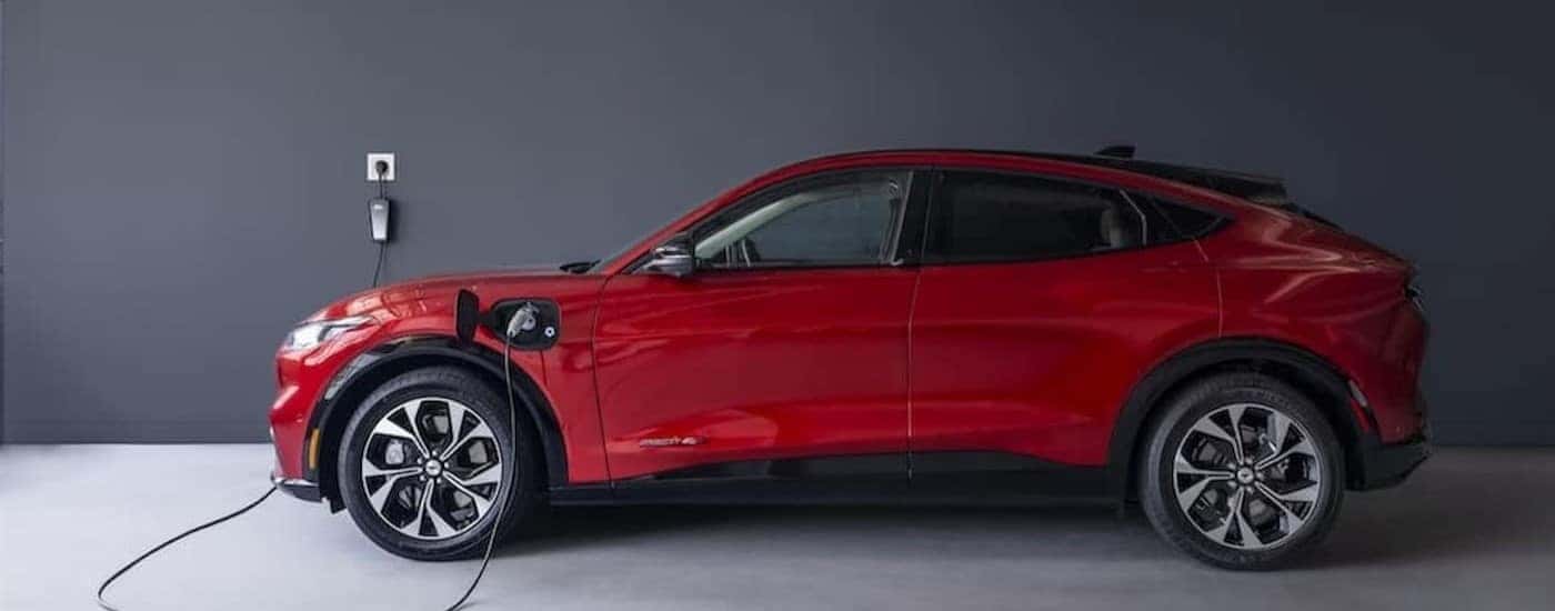 A red 2023 Ford Mustang Mach-E is shown charging in a garage.