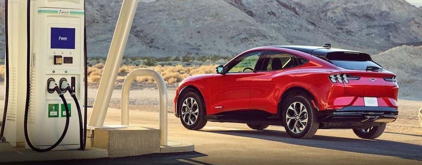 A red 2023 Ford Mustand Mch-E is shown parked near a charge station.