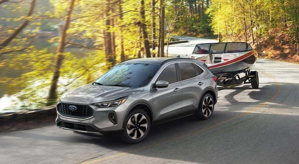 A silver 2024 Ford Escape is shown towing a boat.