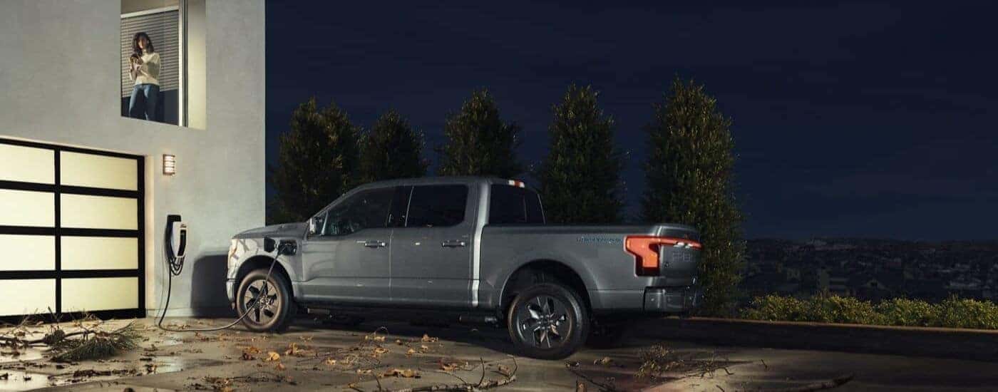 A grey 2022 Ford F-150 Lightning is shown providing back-up power to a house.