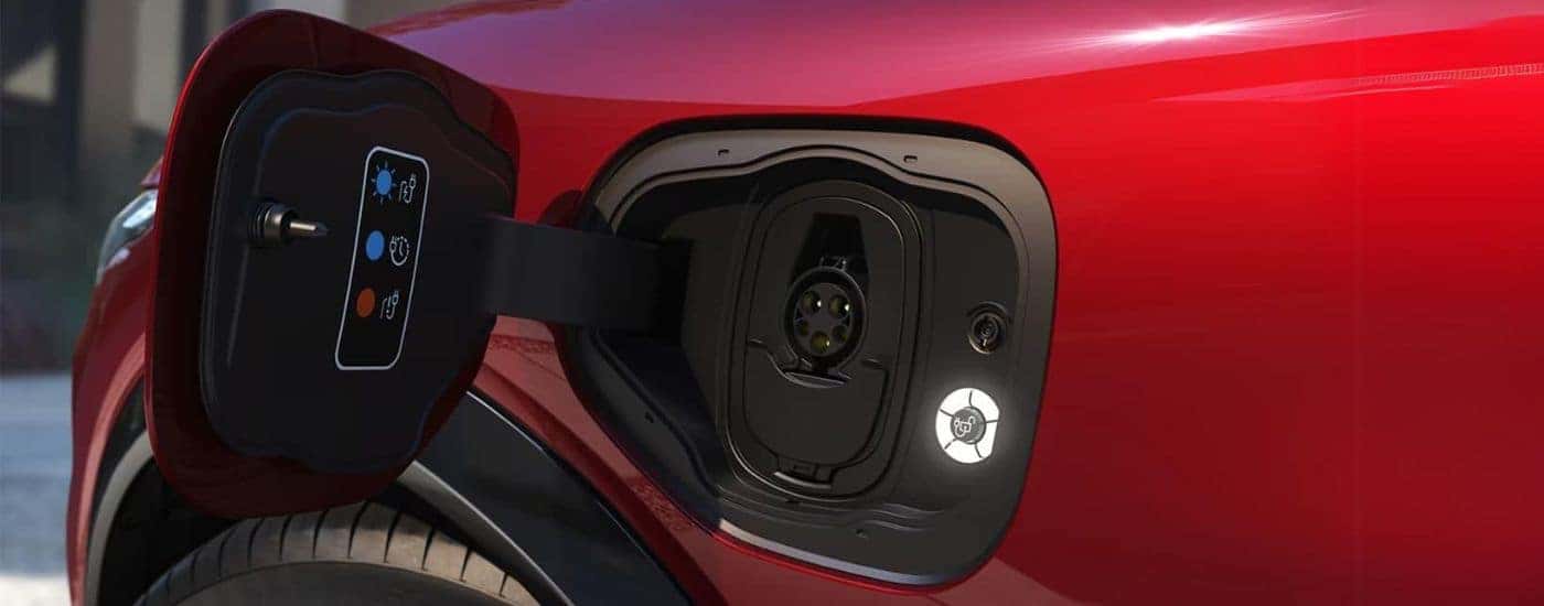 A close up shows the charge port on a red 2022 Ford Mustang Mach-E.