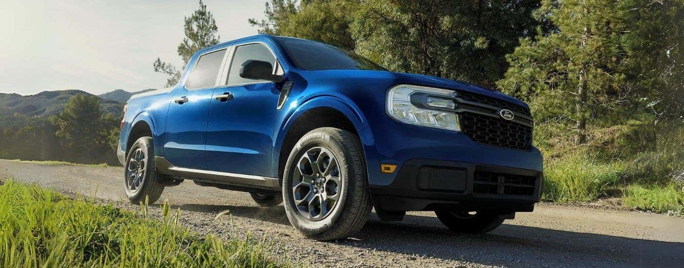 A blue 2024 Ford Maverick Hybrid XLT is shown parked on a trail.