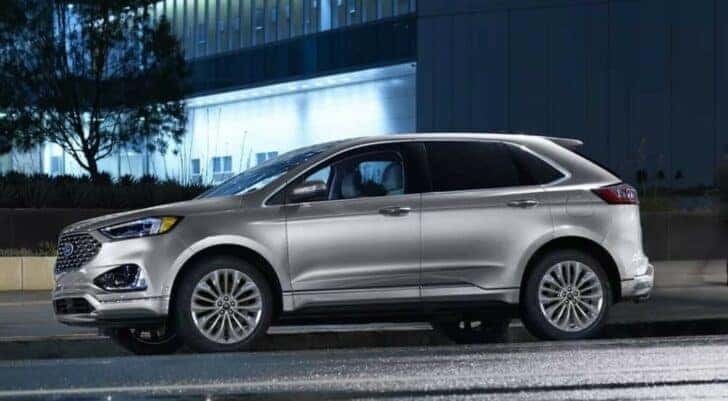 A silver 2024 Ford Edge for sale is shown parked near a building.