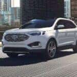 A white 2024 Ford Edge Titanium is shown driving on a bridge after viewing a Ford Edge for sale.
