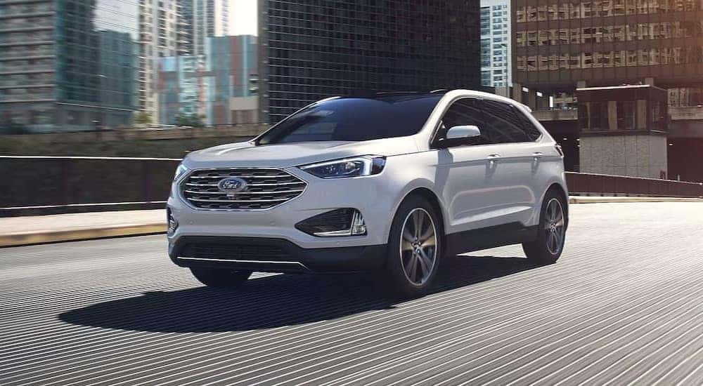 A white 2024 Ford Edge Titanium is shown driving on a bridge after viewing a Ford Edge for sale.