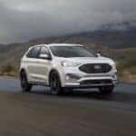 A white 2024 Ford Edge driving on a misty road.