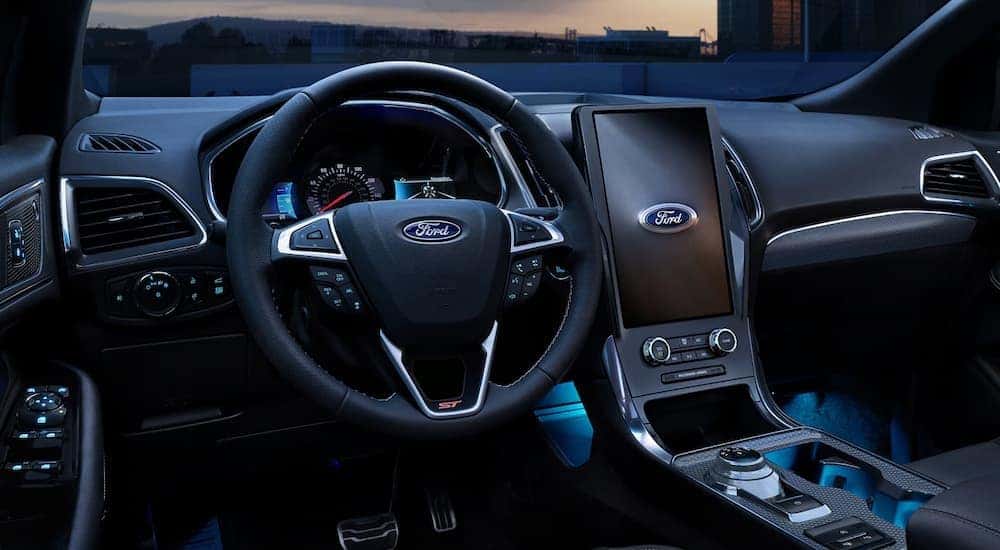 The large infotainment screen and blue ambient lighting in a 2024 Ford Edge for sale.