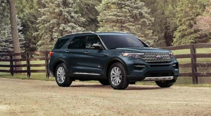A blue 2024 Ford Explorer King Ranch is shown parked on a dirt road.