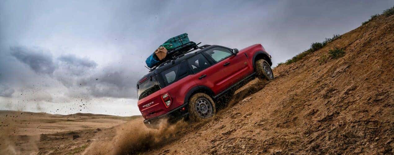 A red 2024 Ford Bronco Sport is shown from the rear at an angle while driving up a hill.