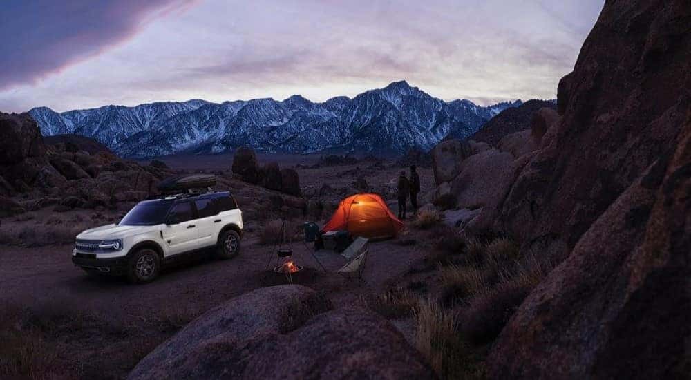 A white 2024 Ford Bronco Sport parked at a mountain campsite at dusk.