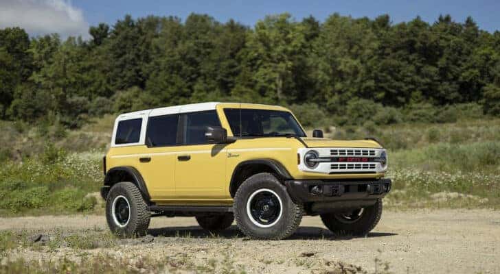 A yellow 2024 Ford Bronco Heritage Edition parked in a field.